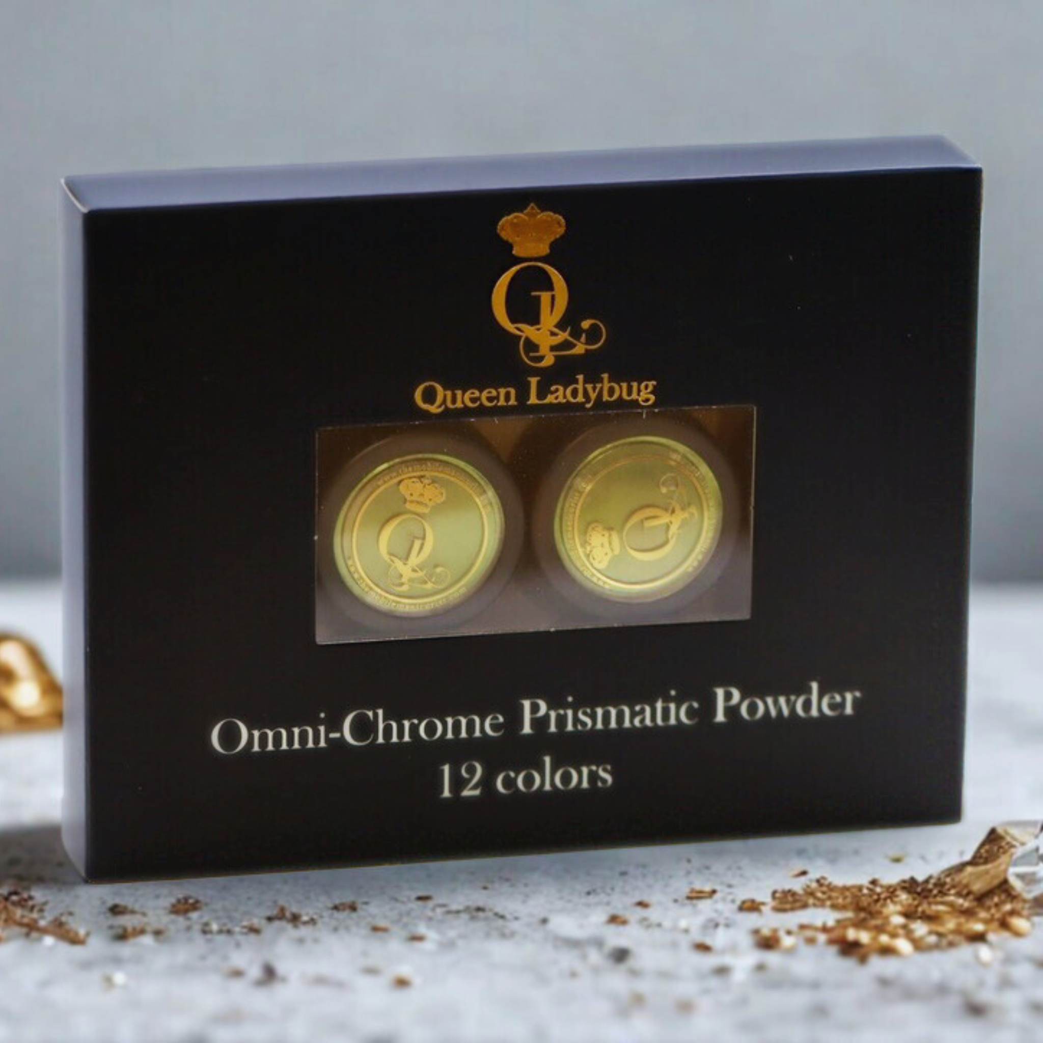 Black packaging of Queen Ladybug Omni-Chrome Prismatic Powder on a light gray background.