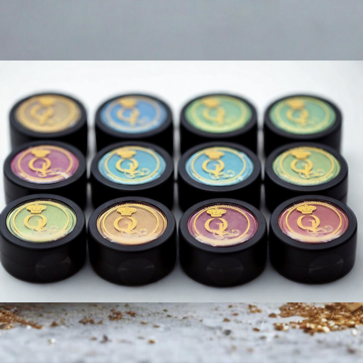 Set of black cylindrical containers with colorful chrome powders inside, sitting on a marble surface.